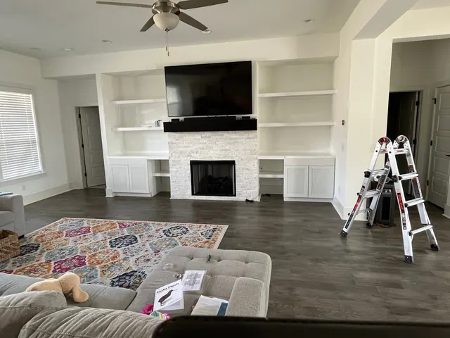 Living room with custom white built-ins around a stone fireplace