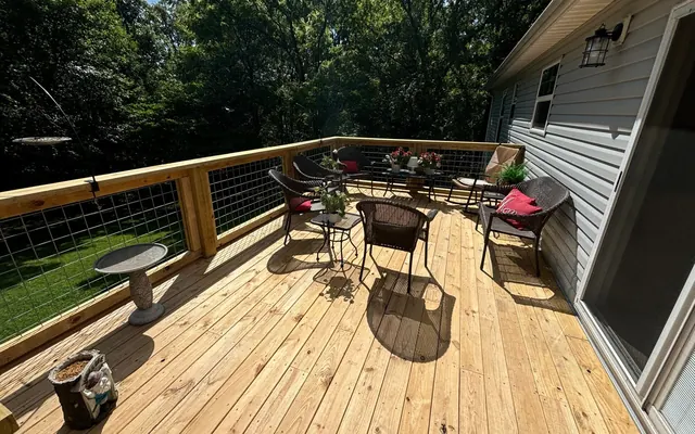 Wide pine deck with wire railings along a house